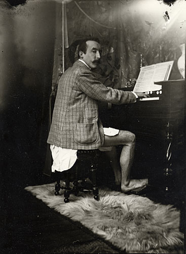 Foto Alphonse Mucha: Paul Gauguin am Harmonium in Muchas Atelier, Paris, um 1893/94